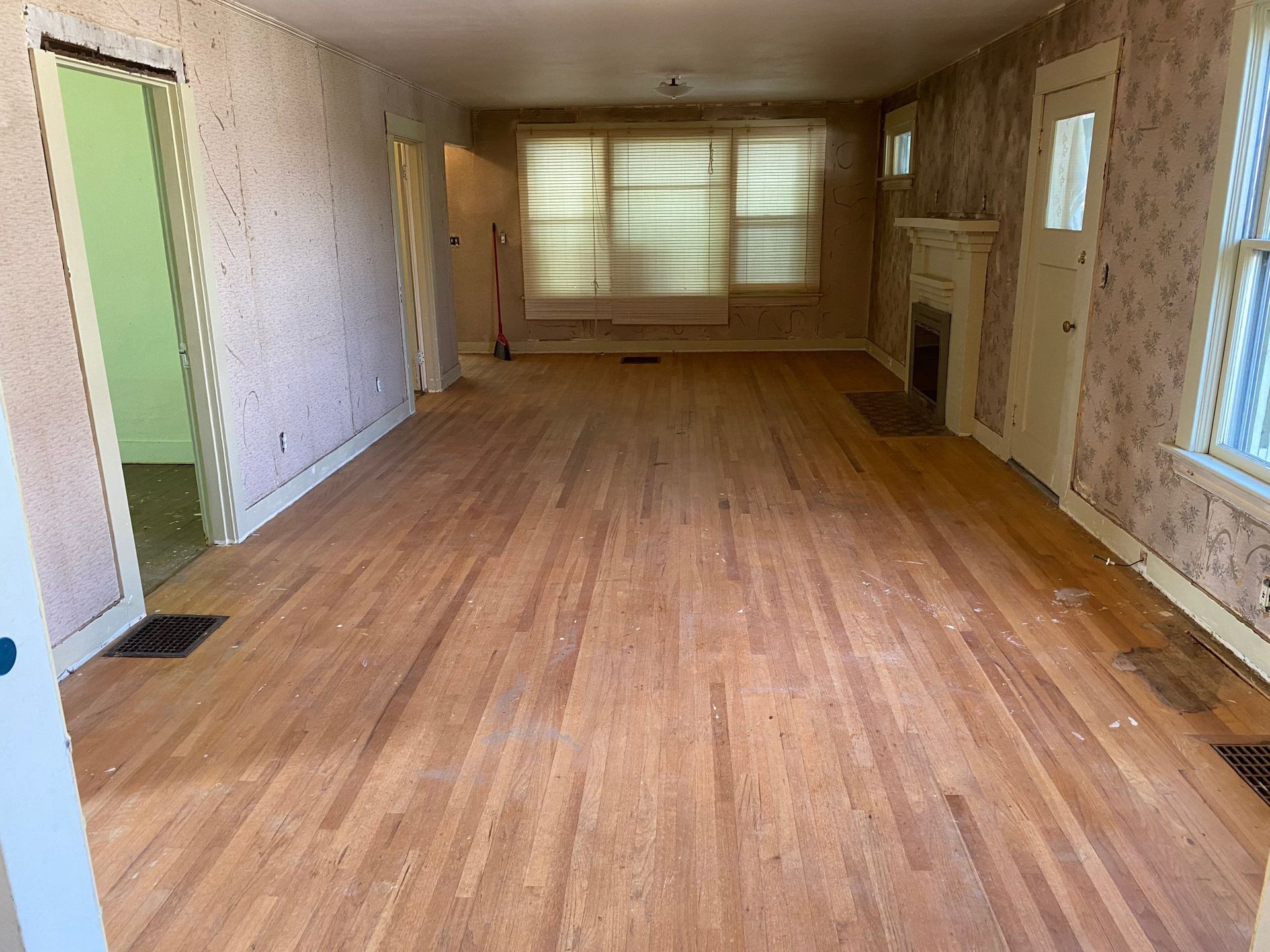 An empty living room with hardwood floors and a fireplace.