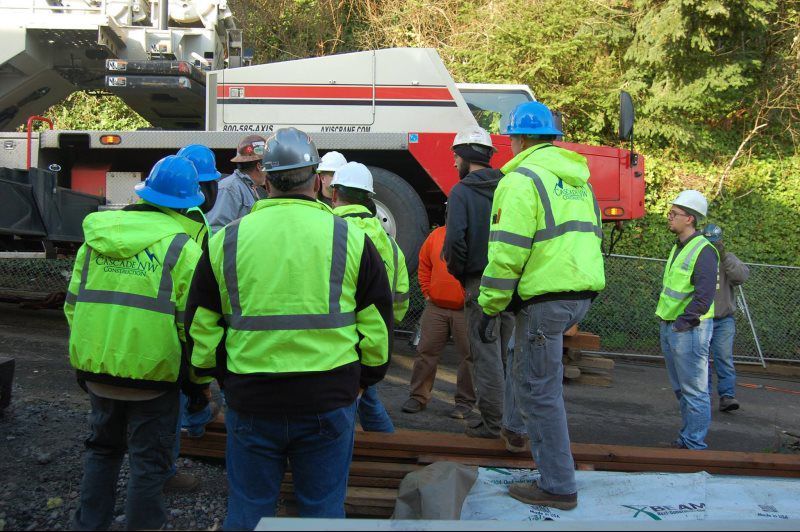 A group of construction workers wearing safety vests and hard hats