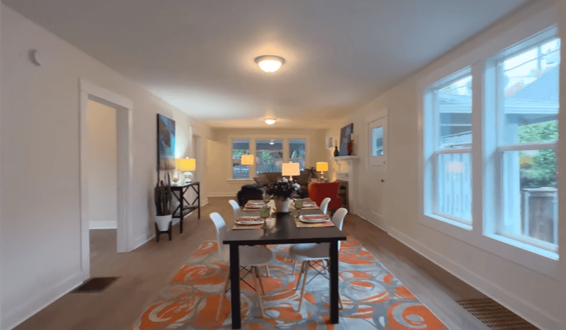 A dining room with a table and chairs and a rug.
