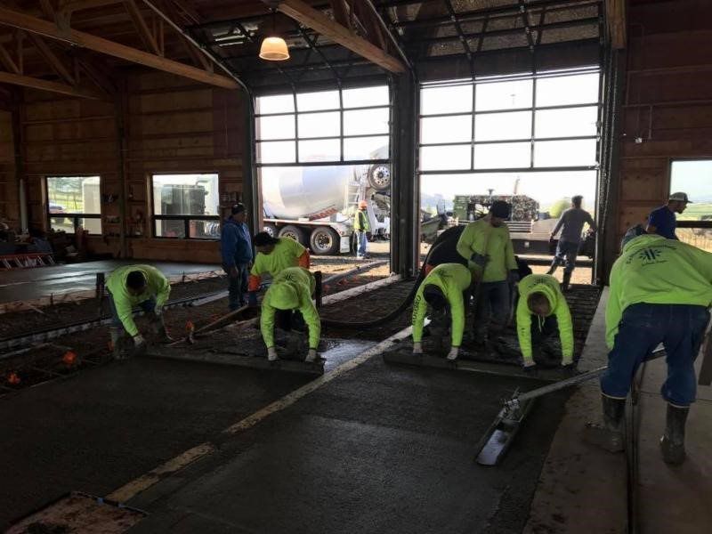 A group of construction workers are working on a concrete floor in a building.