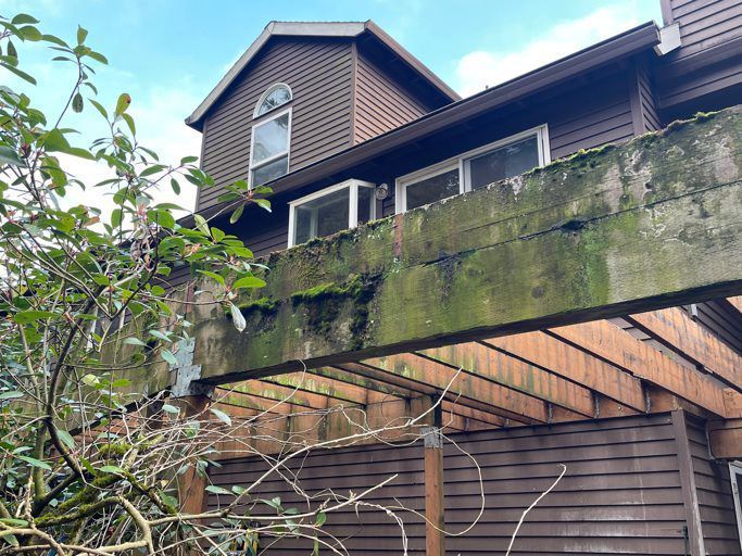 A house with a wooden deck that is covered in moss.