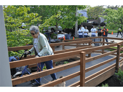 A woman with a walker is crossing a wooden bridge