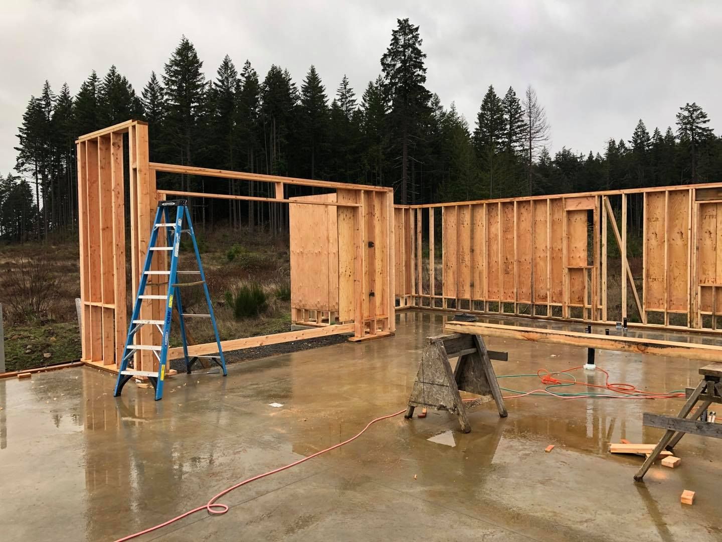 A wooden house is being built with a ladder and a saw.