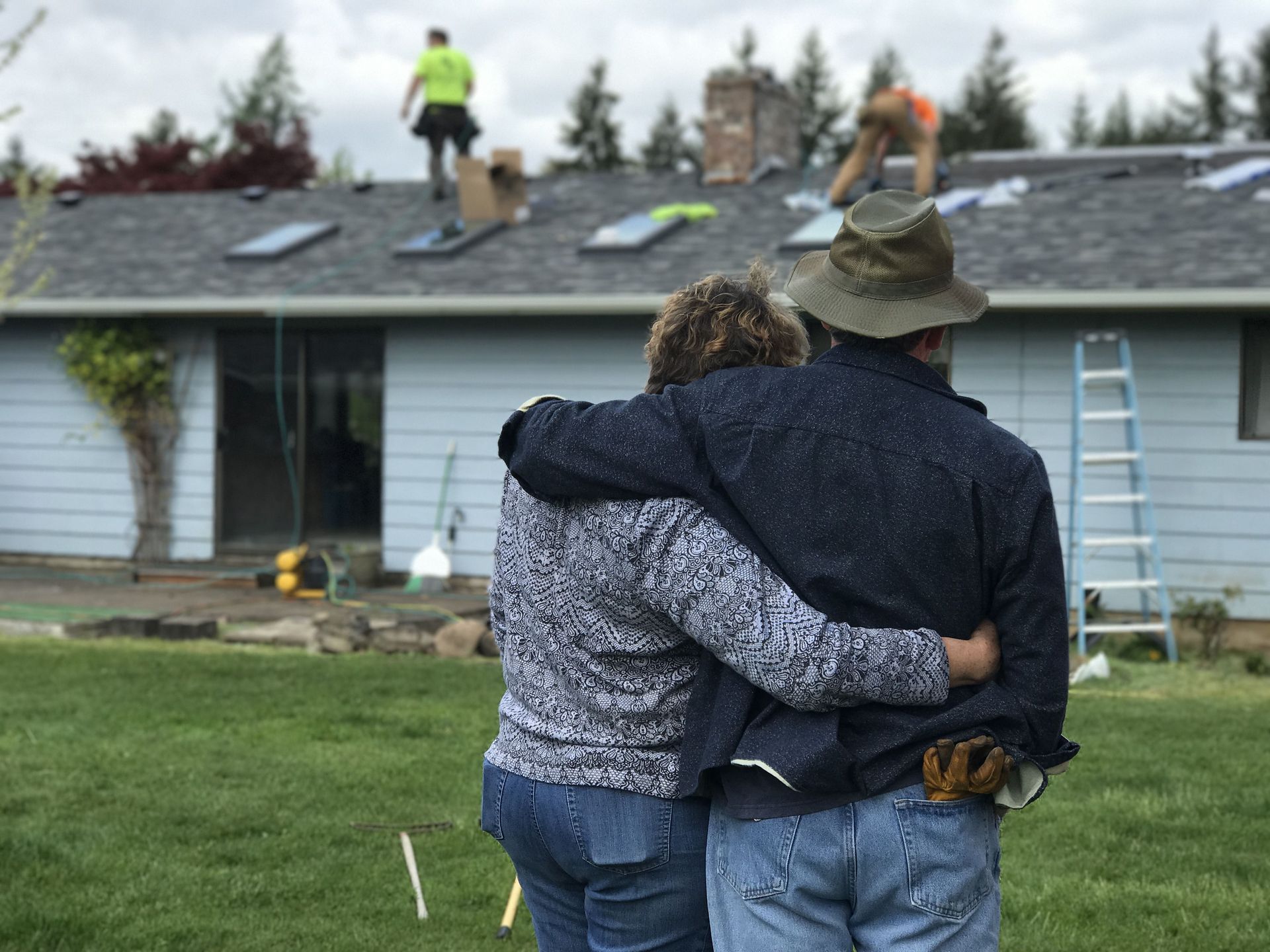 A man and a woman are standing in front of a house that is being remodeled.