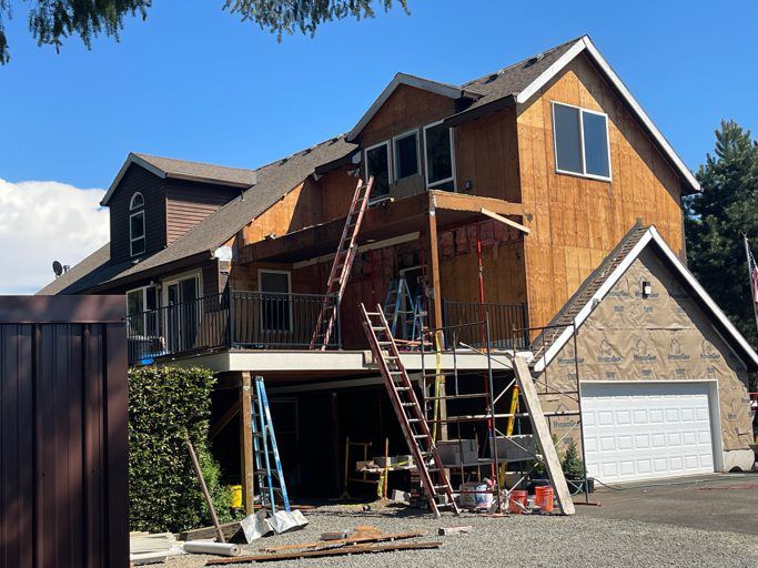 A large house is being remodeled with a deck and stairs.