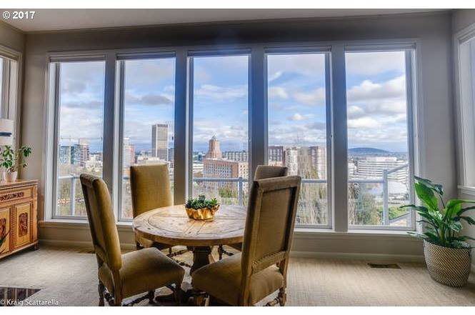 A dining room with a table and chairs and a view of the city.