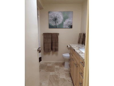 A bathroom with a toilet , sink , and a painting of dandelions on the wall.