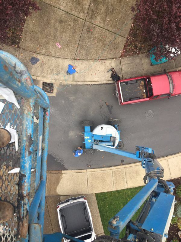 A red truck is parked on the side of the road next to a blue crane.