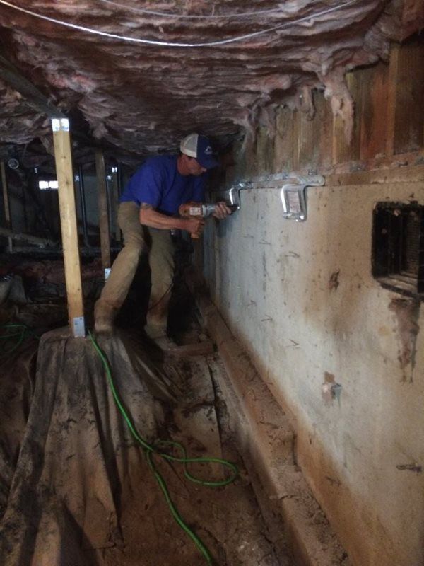 A man is working on a wall in a basement.