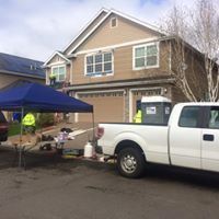 A white truck is parked in front of a house with a blue canopy.