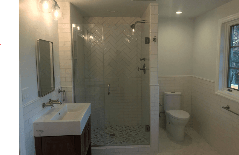 A bathroom with a sink , toilet , shower and mirror.