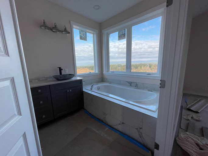 A bathroom with a tub , sink , and window.