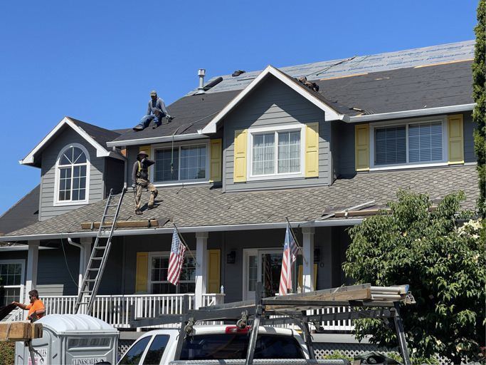 Two men are working on the roof of a house.