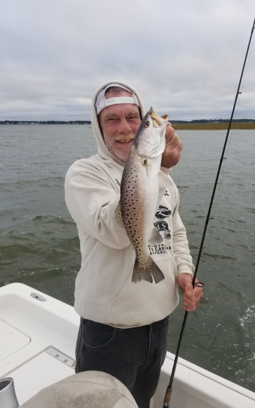 A man is holding a fish on a boat in the water.