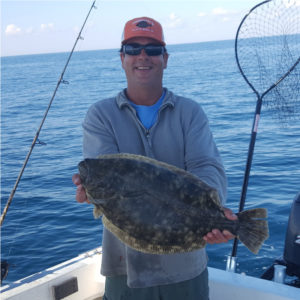 A man on a boat holding a large fish
