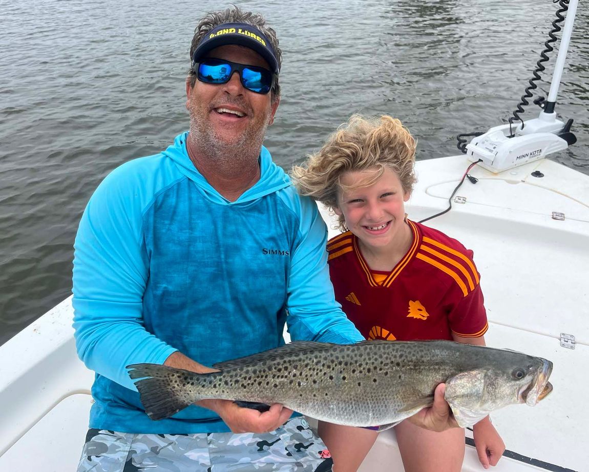 A man and a boy are holding a large fish on a boat.