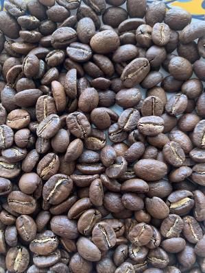 Granos de café de color blanco verdoso con algunas bayas rojas, probablemente después del procesamiento.