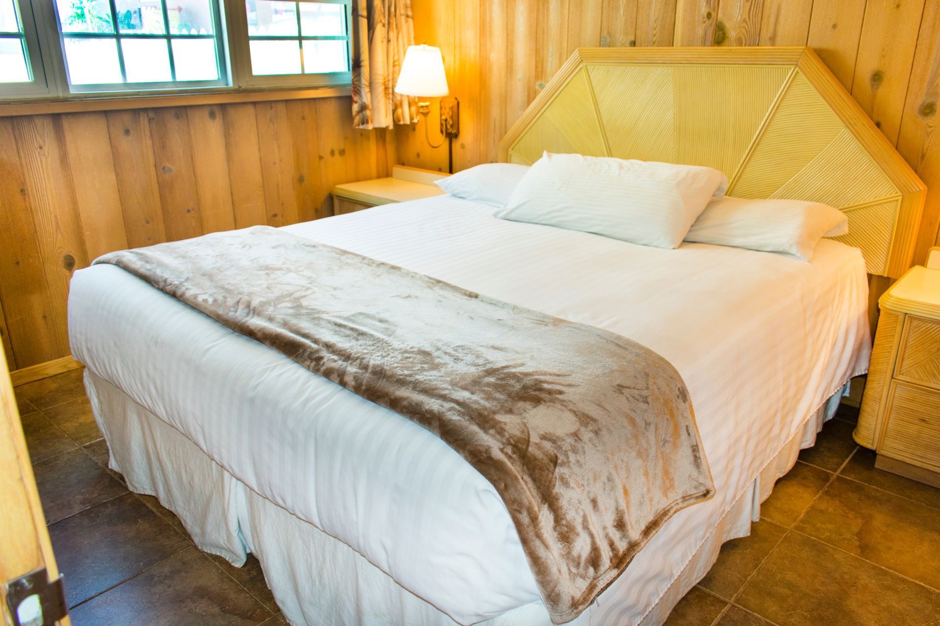 Bedroom with a large bed, wooden walls, bedside tables, and a window.