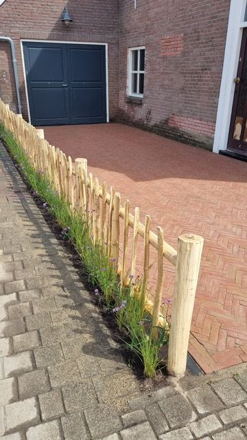 Een houten schapenhek omringt een oprit voor een huis.