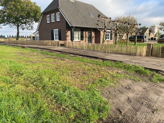 Een bruin huis met een robinia houten hekwerk ervoor.