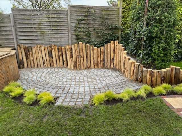 Kastanje houten palen omringt een stenen terras in een tuin.