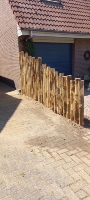 Afscheiding van kastanje palen omringt een oprit voor een huis.