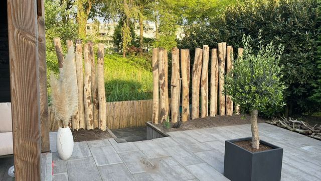 Terras met kastanje palen als divider in de tuin.