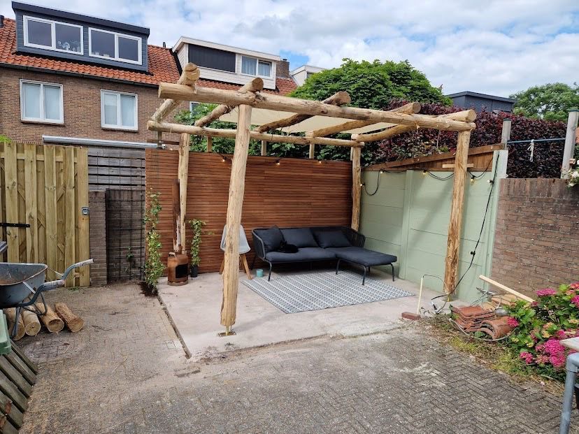 Een bank onder een pergola van robinia palen in de achtertuin.