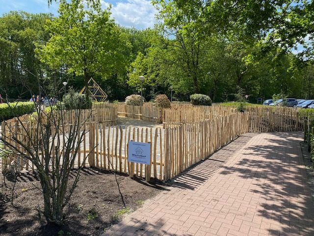 Een robinia houten hek omringt een stenen loopbrug in een park.