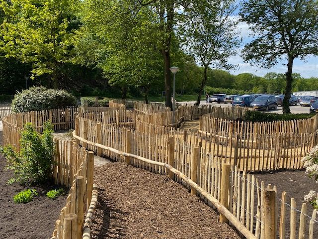 Een houten schapenhek omringt een pad in een park.