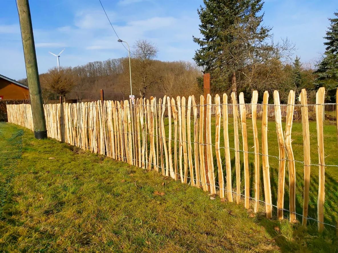 Midden in een grasveld staat een houten schapenhek van robinia.