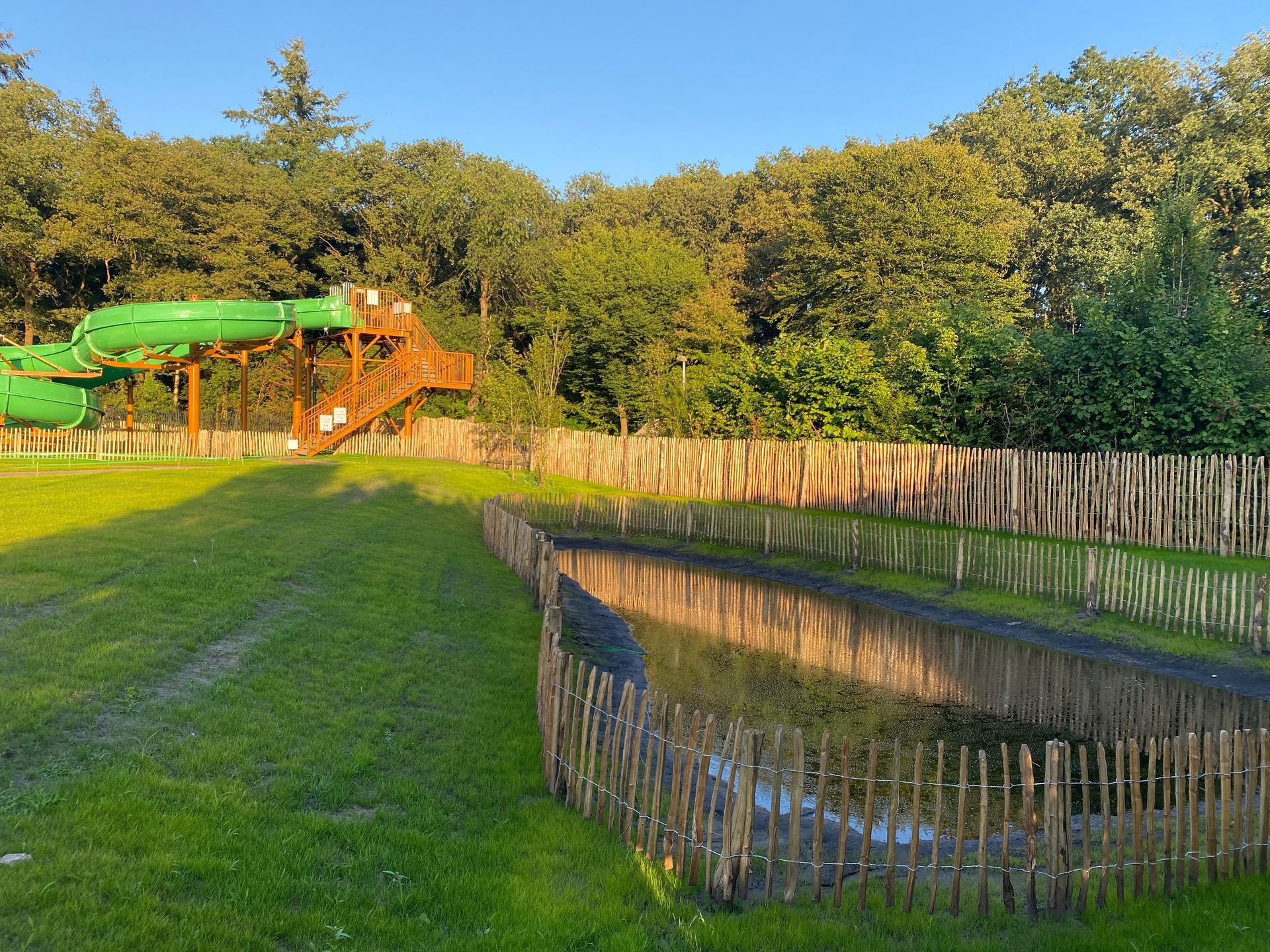 Een waterglijbaan is omgeven door een houten hek in een park.