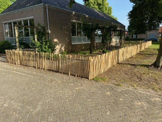 Een houten hek omringt een huis aan de kant van de weg.