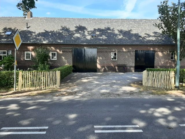 Een groot gebouw met robinia hekwerk ervoor staat naast een weg.