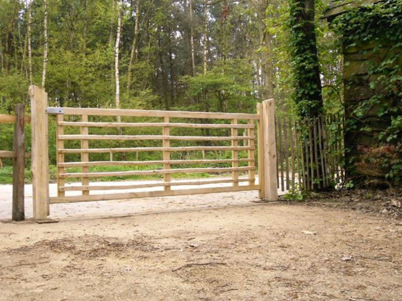 Midden op een onverharde weg staat een houten hek.