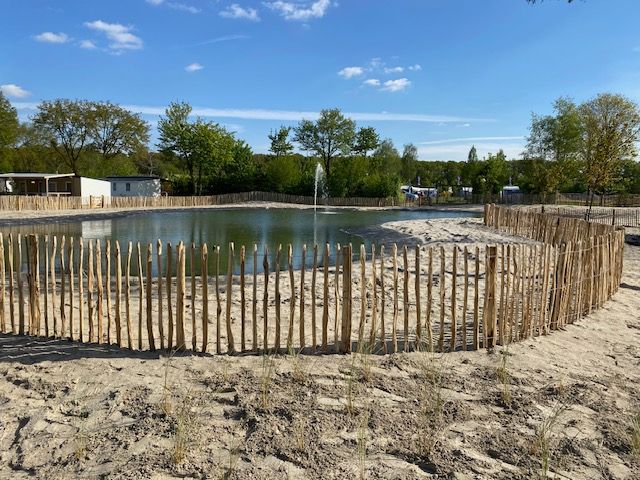 Een schapenhek omringt een vijver met op de achtergrond een fontein.