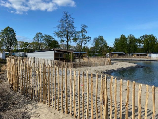 Een houten schapenhek omringt een klein eiland midden in een meer.