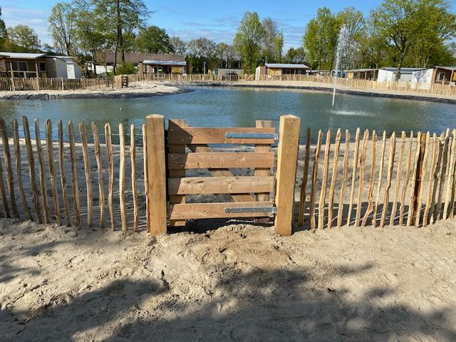 Een robinia landhek omringt een vijver met op de achtergrond een fontein.