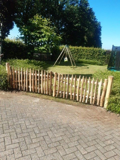 Een kastanje houten tuinpoort met een schommel op de achtergrond