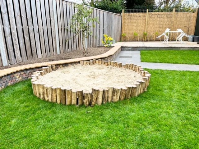 Een zandbak gemaakt van robinia palen in een achtertuin.