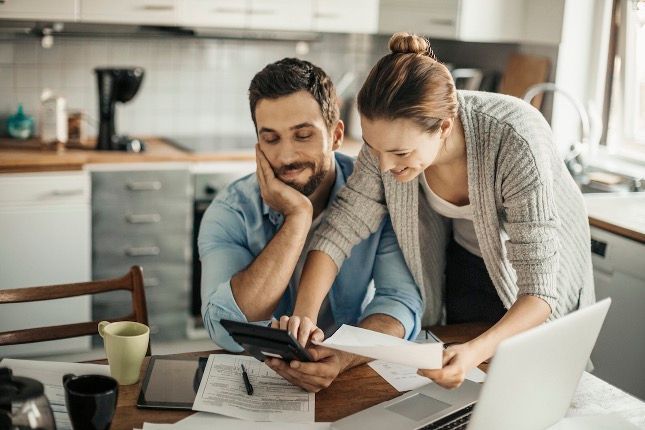 Couple Smiling looking at document to see if they are ready to buy a house