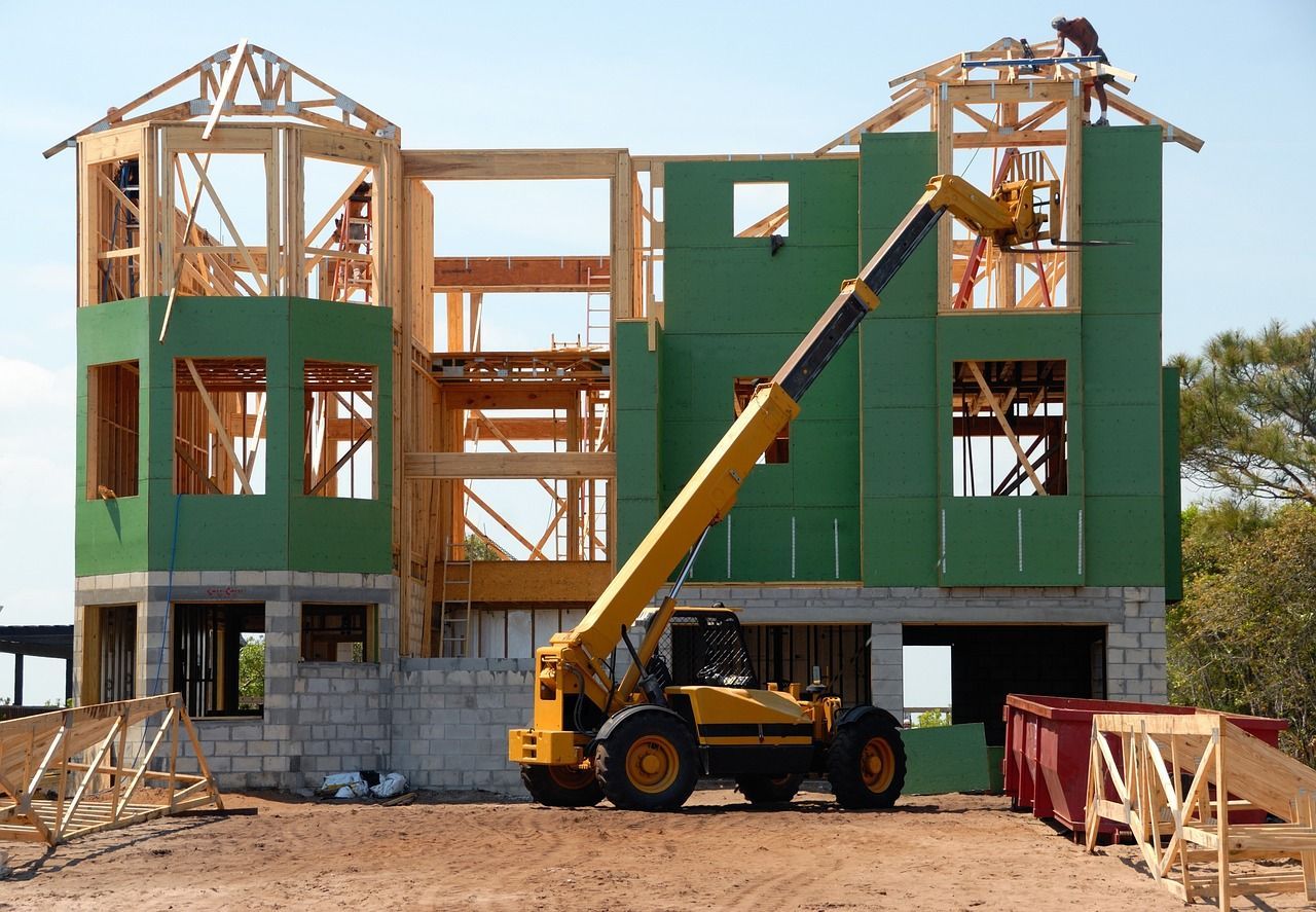 Construction of a new home supported by a yellow crane, showcasing the process of home building.