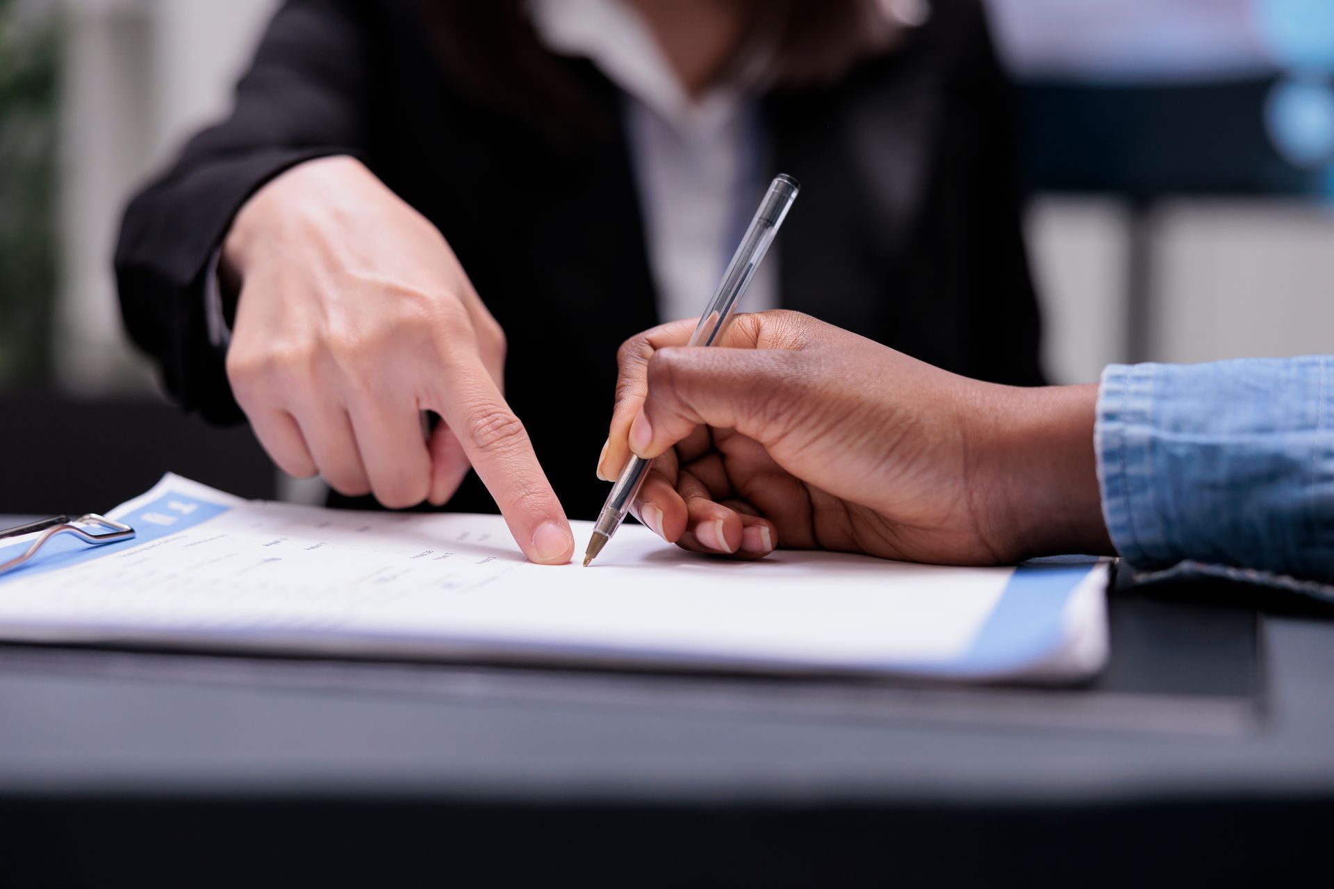 Close-up of two people reviewing and signing a document together, symbolizing co-borrowing or co-sig