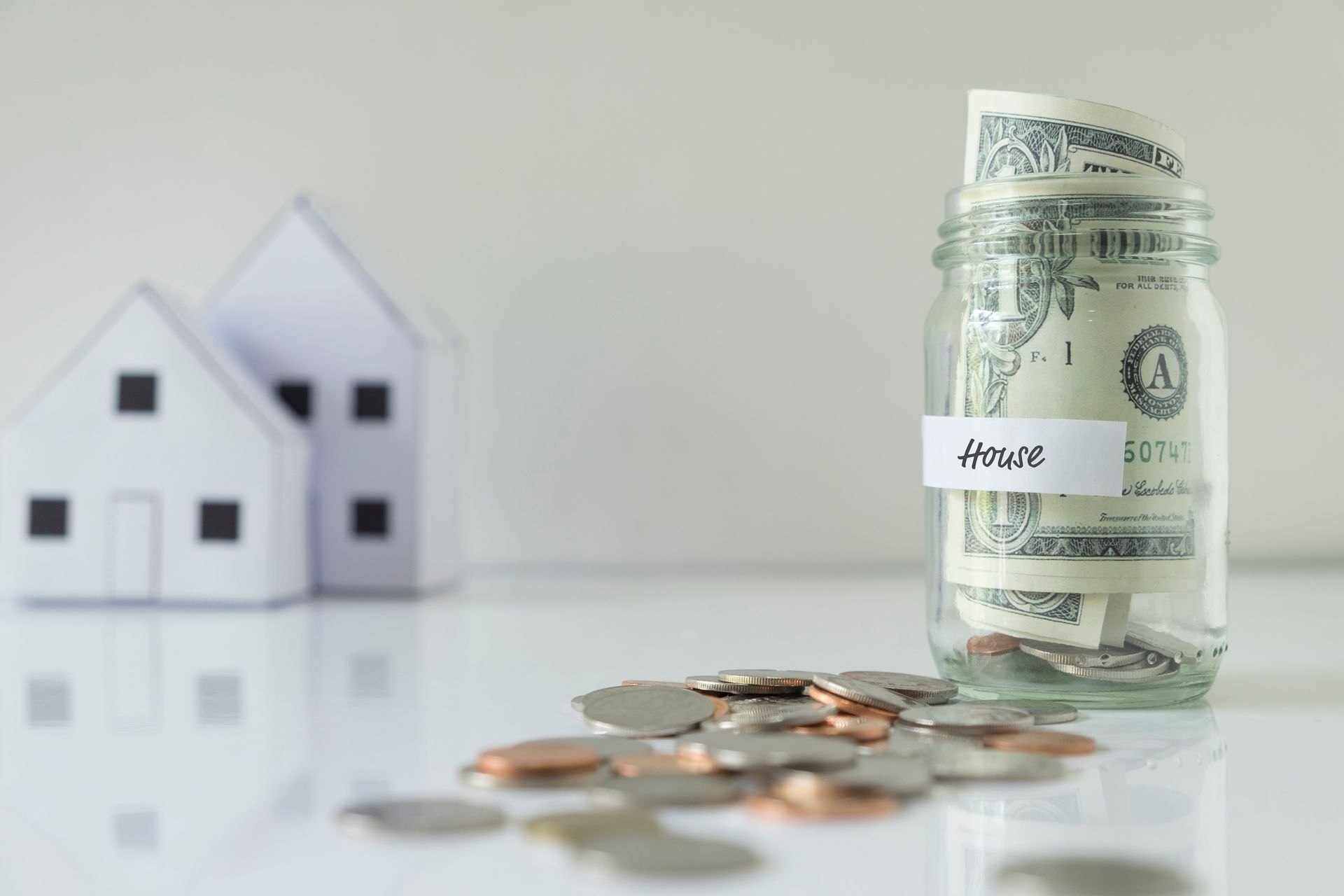 'House' with money inside, surrounded by coins, symbolizing using 401(k) savings for a home