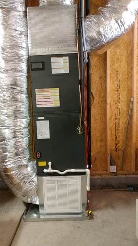 HVAC unit in a framed wall cavity, silver ductwork, with filter visible.