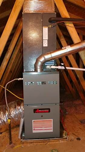 Furnace in attic, grey metal, venting to the right, sitting on a metal platform, wood beams behind it.