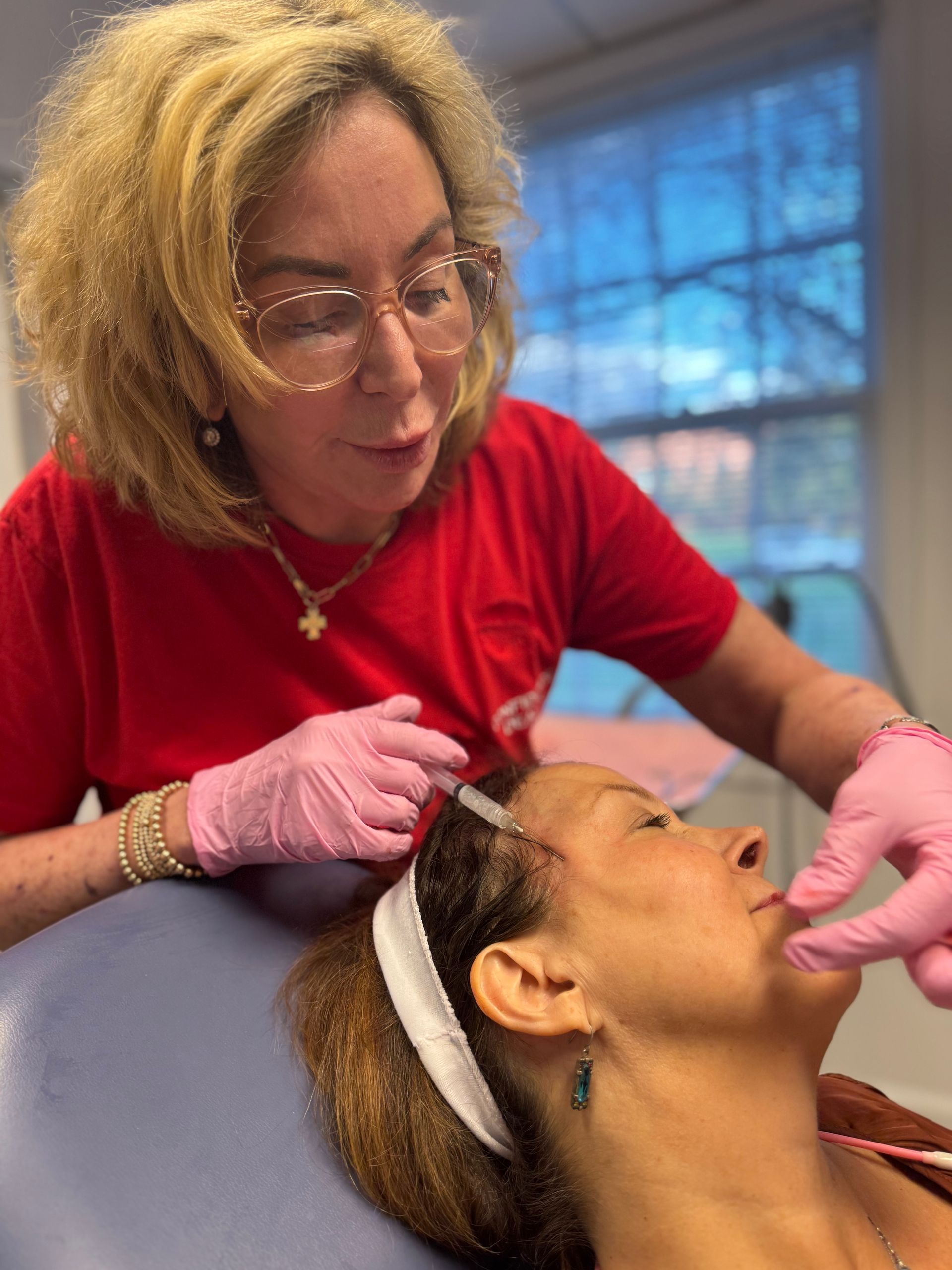 A woman is giving a woman a massage with cucumber slices on her eyes.