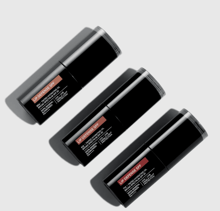 Three tubes of lip gloss sit on a white surface