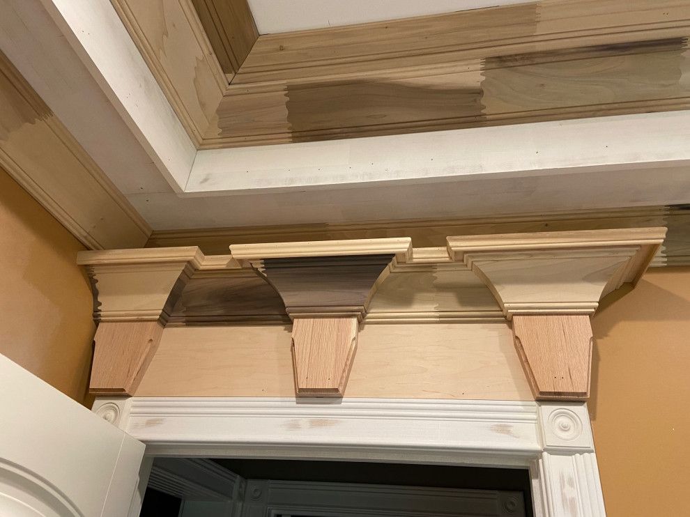 A wooden molding is being installed on the ceiling of a room.