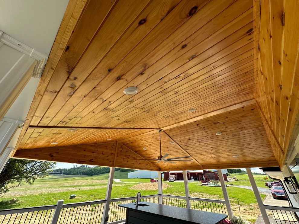 A porch with a wooden ceiling and a ceiling fan.